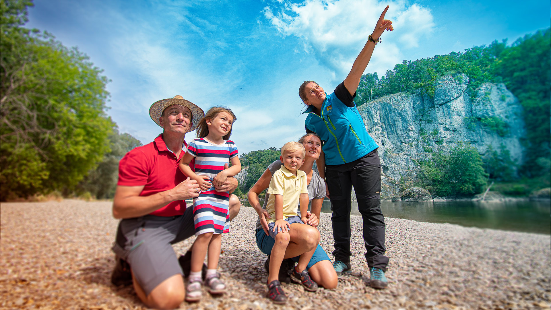 Mitarbeiterin im Naturschutz zeigt einer Familie mit Kindern etwas in der Ferne.